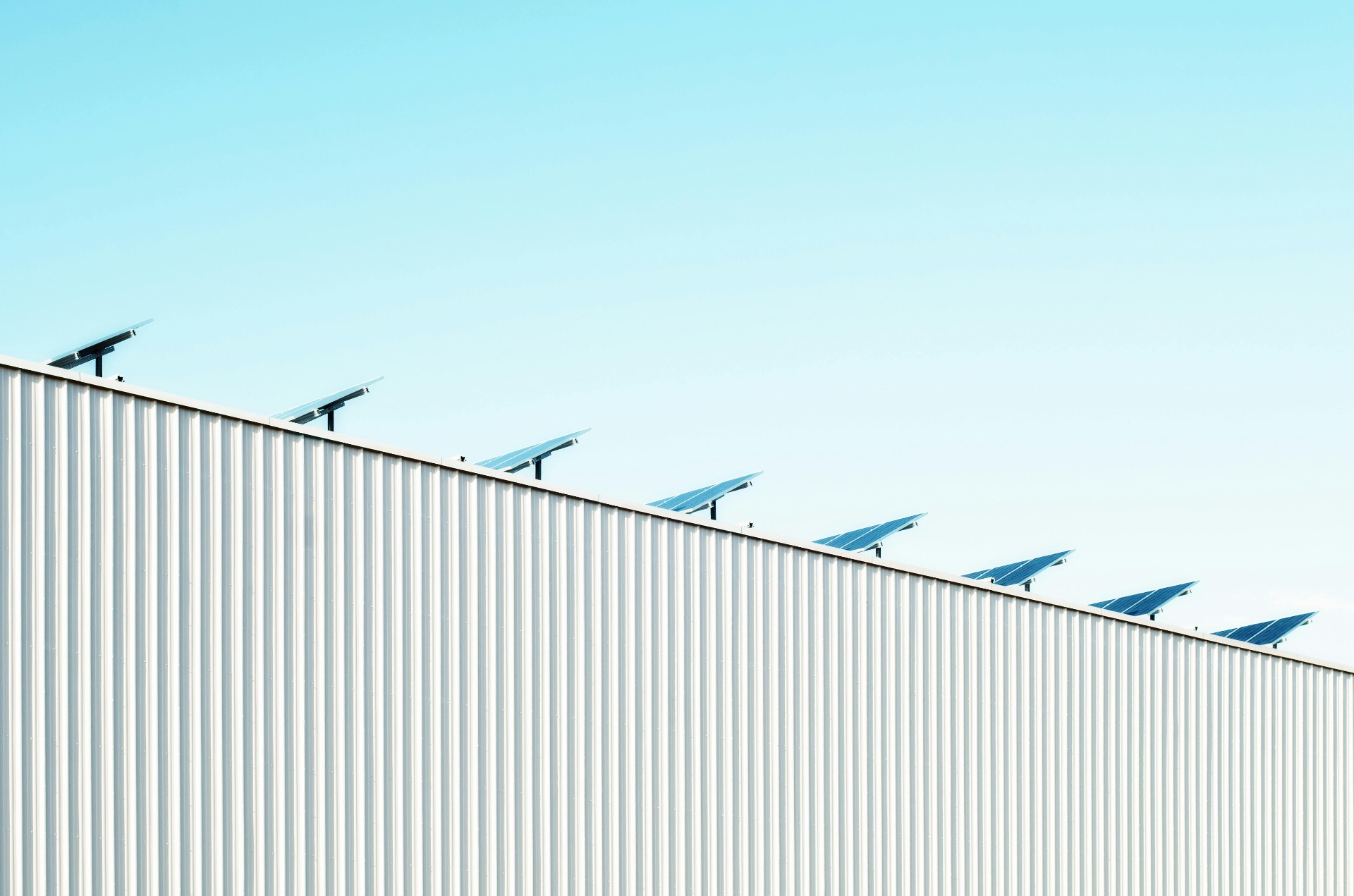 Industrial roof-mounted solar panels against a clear sky